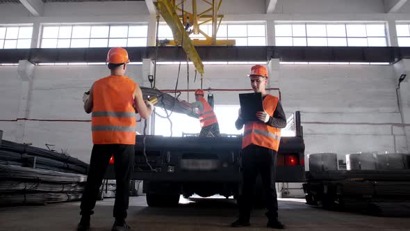 Workers loading metal structures with a crane onto a truck