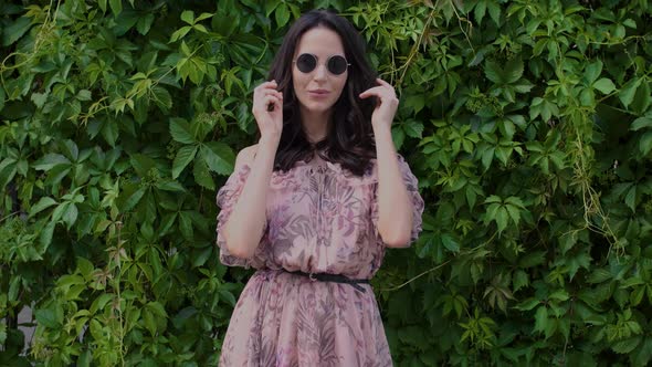 Stylish Hipster Girl Posing Over Green Leaves Bush Background