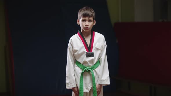 A Little Boy Doing Taekwondo  Bows in Front of a Camera