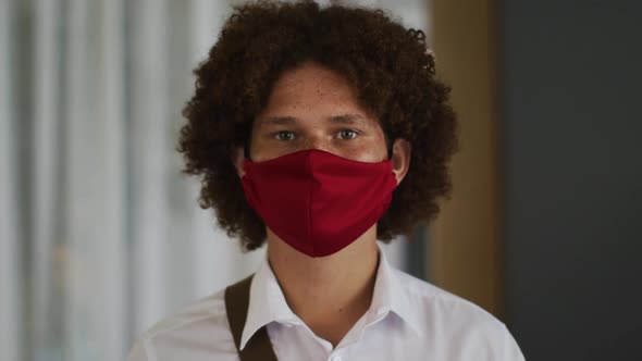 Portrait of mixed race man with curly hair wearing red face mask