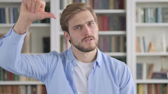 Portrait of Man Showing Thumbs Down Gesture