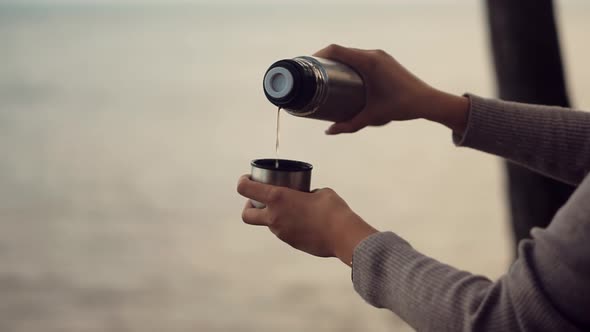 Woman Pouring Coffee Into Cup. Hot Tea From Thermos. Holiday Vacation Trip And Relaxing Moment.