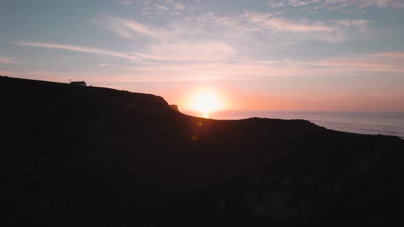 AERIAL: Sideways dolly revealing coastgaurd lookout and orange sunrise, Rhossili Gower, 4k Drone