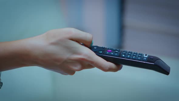 Television Remote Control in Woman Hands Pointing to Tv