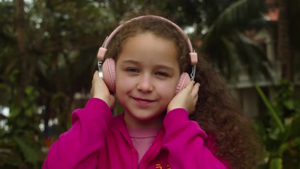 Footage Out of Focus Portrait of Cute Little Girl With Headphones Listening To Music