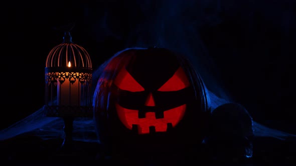 Scary laughing pumpkin and an old skull over the frightening gothic background.