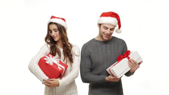  Young Couple in Sweater Holding Present and Treat Like a Child on White Background.