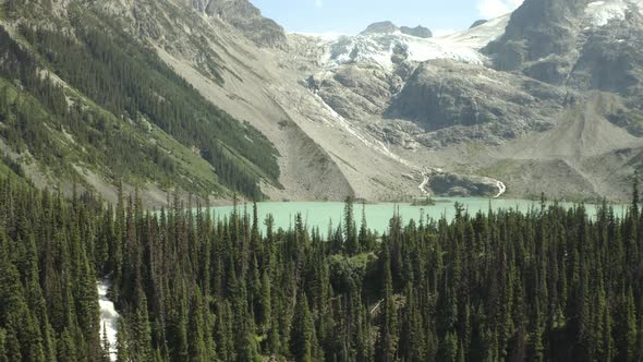 Joffre Lakes in BC Canada, Drone shot of trees and turquoise lake with the glacier on the background