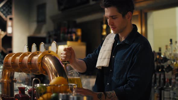 Male bartender beer at bar to the clients. Shot with RED helium camera in 8K.