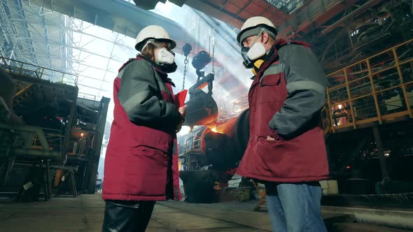 Metallurgical Factory with Two Industrial Workers Talking