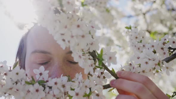 Man Smells Pleasant Aroma of White Flowers on Tree Branch