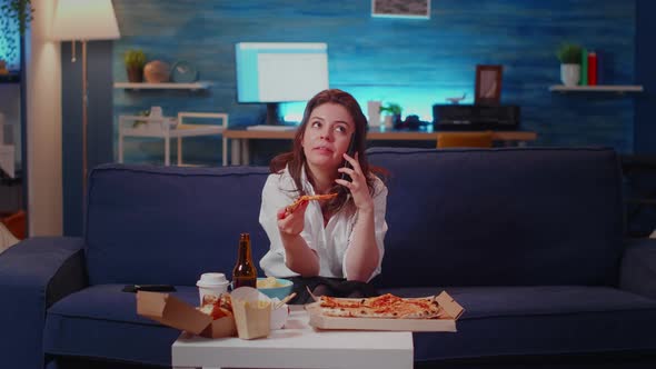 Annoyed Woman Talking on Phone Call While Holding Slice of Pizza