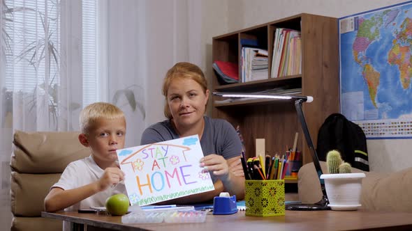 A Mother and Son at Home They Hold a Sheet with the Inscription STAY AT HOME