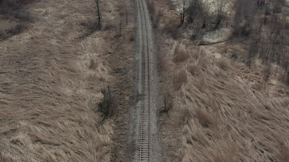 Railway line in the field with dry plants 4K aerial video