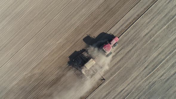 Countryside and Agriculture Farm Tractors Plow the Earth in Field Dust in the Field View From Height