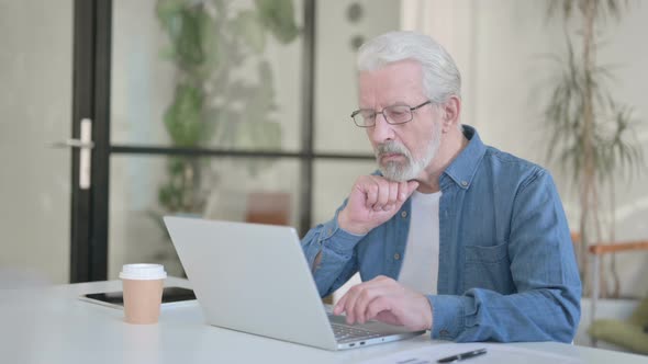 Senior Old Man Thinking While Using Laptop in Office