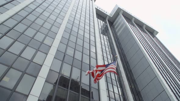Low Angle Shot of an American Flag Waving in Front of a Skyscraper