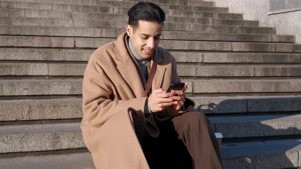 Positive Arabian man texting by phone