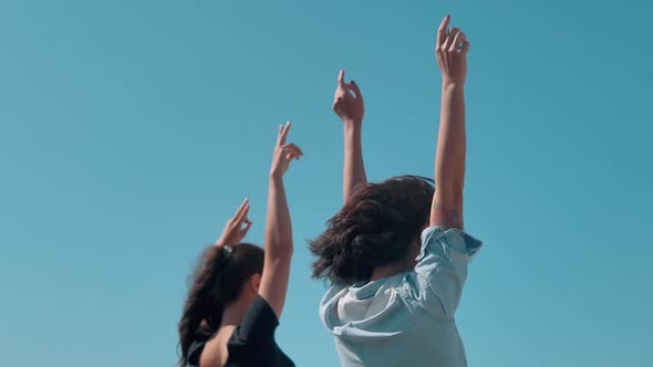 Girls Standing with Open Arms Against the Blue Sky