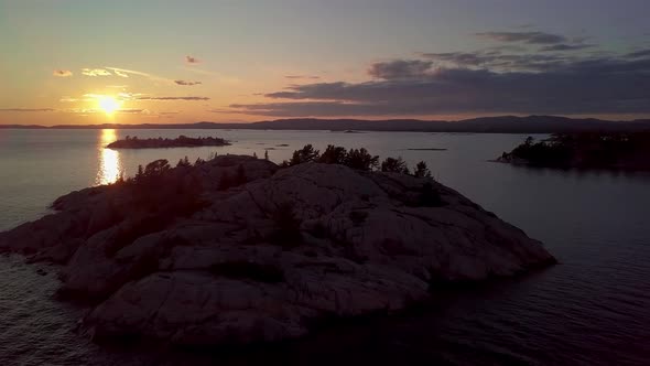 Rocky Island with Pine Trees in Blue Lake at Sunset, Drone Aerial Wide Dolly In. Flying over Wild Ge