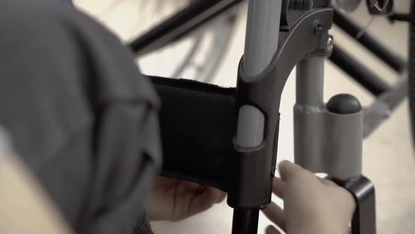 Young Guy Fixes the Leg Fastener to the Wheelchair