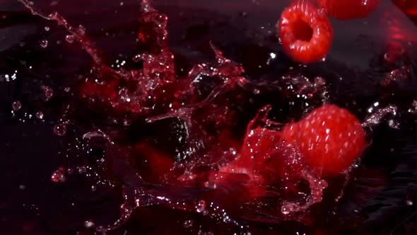 Red Raspberries are Falling Into the Sweet Juice with Drops and Splashes