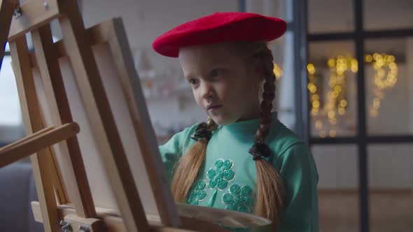 Dreaming Little Girl Creating Picture on Easel alt