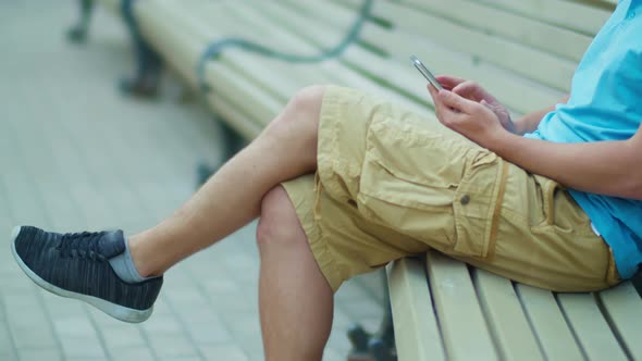 A Tourist Sits with a Mobile Phone in His Hands on a City Bench Camera Tracking