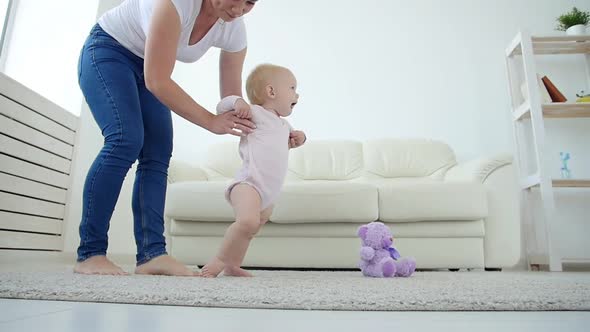 Baby Taking First Steps with Mother's Help at Home