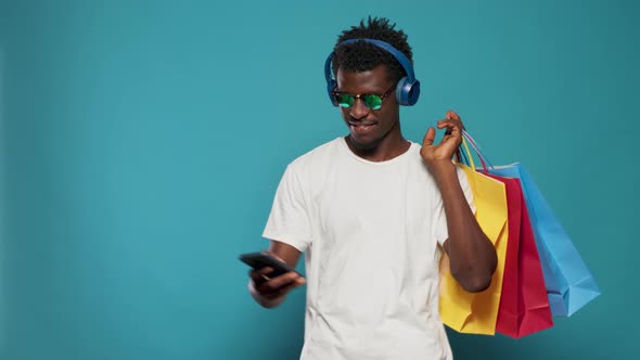 Playful Man Taking Pictures with Shopping Bags on Smartphone