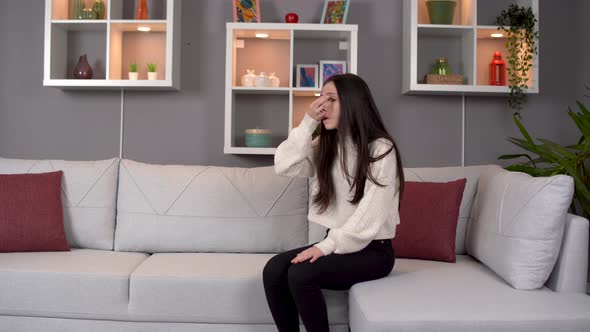 Young woman suffering from headache at home.