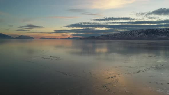 Flying backwards over frozen lake at sunset