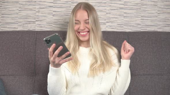 Exited smiling girl using smartphone, celebrating success, victory, achievement.