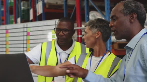 Warehouse staff meeting around a laptop 4k