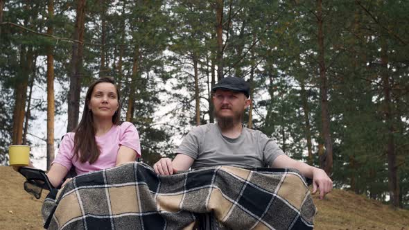 A Married Couple are Sitting Covered with a Blanket in Nature Holding Hands in the Forest