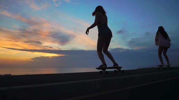 Silhouette of Girls on a Skateboard Ride on the Road Against the Rock and the Sky Beautiful at