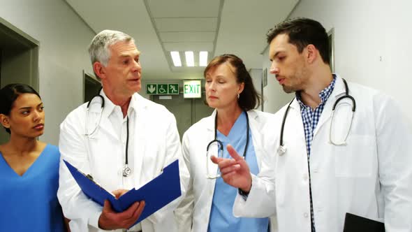 Doctors and nurse discussing over medical report while walking in corridor