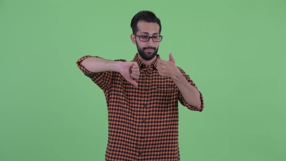 Confused Young Bearded Persian Hipster Man Choosing Between Thumbs Up and Thumbs Down