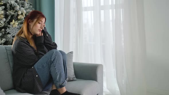 Lonely Young Woman Spending Christmas Alone. Portrait of Beautiful Redhead Caucasian Lady Sitting on