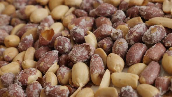 Salted Arachis hypogaea  slow pan 4K 2160p 30fps UltraHD footage - Pile of roasted peanuts on white 