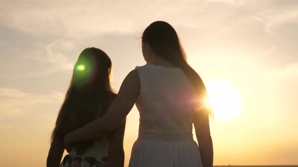 Mom Hugs Daughter, They Admire Beautiful Sunset. Concept of Happy Family of Children and Children