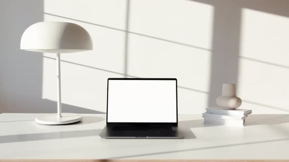 Camera zooming in on a laptop which is switched on and placed on a white table adorned with beautifu