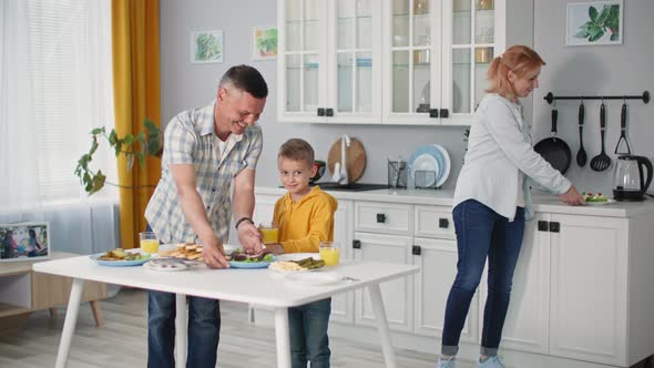 Friendly Family Together with Male Child Set Table for Joint Dinner at Home Backdrop of Kitchen