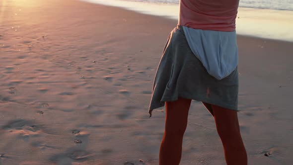 Senior woman standing with arms outstretched on beach