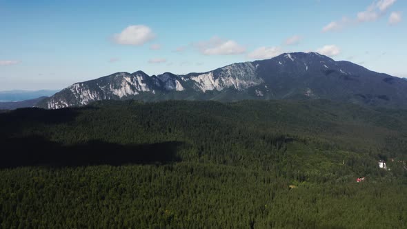 Aerial View Of Verdant Forest With Postavarul Massif In The Background Near Predeal In Romania.