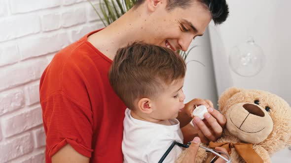 Caucasian Man in His 30s Lets His Little Son to Carefully Blow a Candle