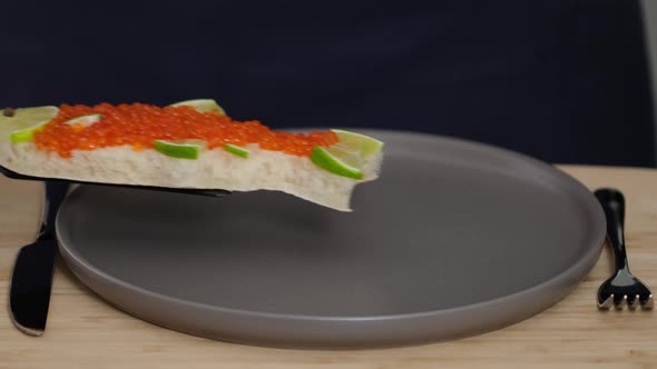 Sandwich with red caviar in shape of fish with lemon put on plate. Seafood