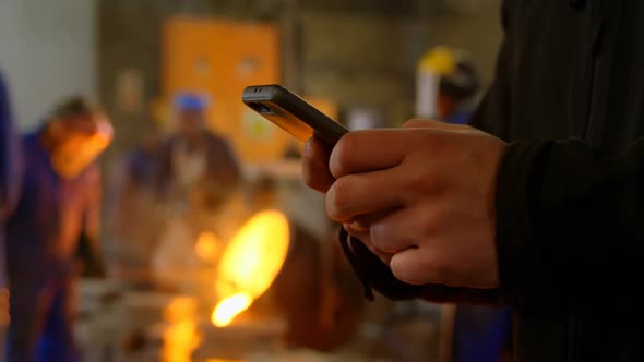 Male worker using mobile phone in workshop 4k