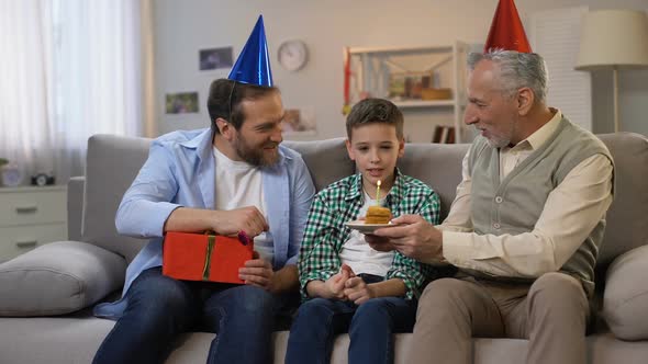 Granddad and Dad Congratulating Preteen Boy on B-Day, Giving Gift Box and Cake