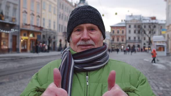 Stylish Old Senior Man Tourist Smiling Showing Thumbs Up in Winter City Center of Lviv Ukraine